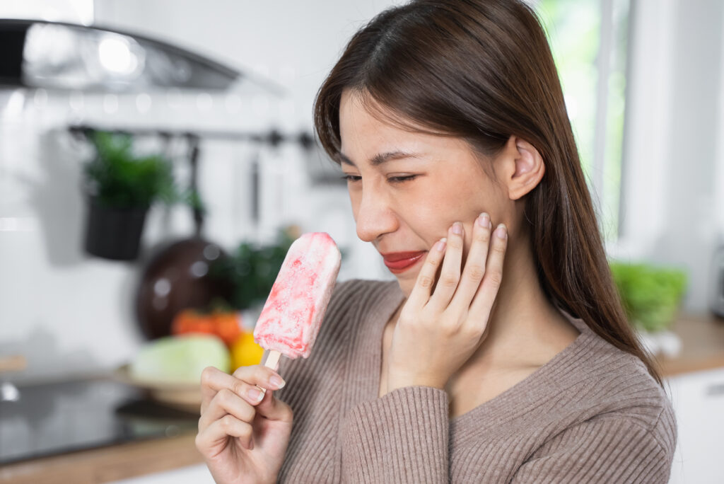 Asian Woman touching her chin feeling sensitive teeth when eatin