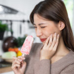 Asian Woman touching her chin feeling sensitive teeth when eatin