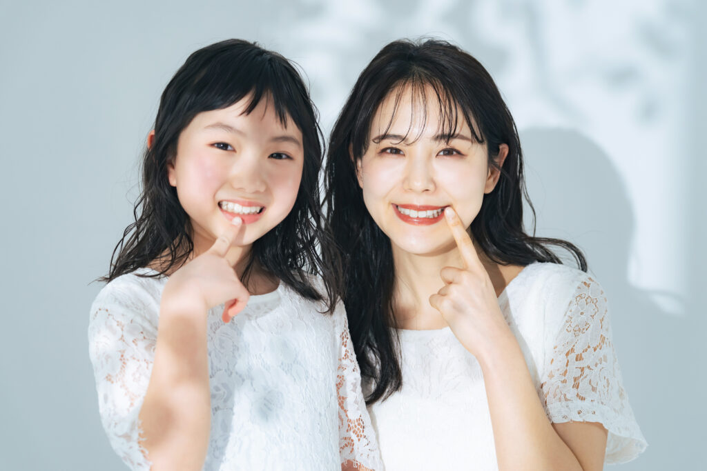 A woman and a girl showing teeth Parent and child dental care image