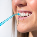 Closeup of woman with perfect smile using water flosser or oral irrigator
