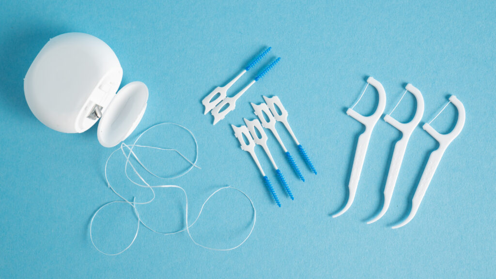 Home dental care kit. Different tools for dental care on blue background. Floss picks floss interdental brush. Top view. High quality photo
